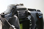 Krytka hledáčku u Canonu 400D přidělaná stále na řemínku fotoaparátu